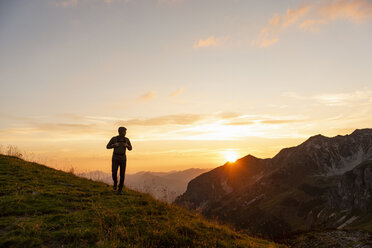 Deutschland, Bayern, Oberstdorf, Mann auf einer Wanderung in den Bergen bei Sonnenuntergang - DIGF04995