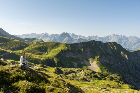 Deutschland, Bayern, Oberstdorf, Mutter und kleine Tochter auf einer Wanderung in den Bergen, die eine Pause mit Blick auf die Aussicht machen, lizenzfreies Stockfoto