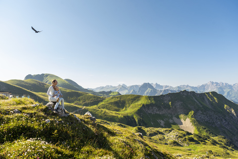 Germany, Bavaria, Oberstdorf, mother and little daughter on a hike in the mountains having a break looking at view stock photo