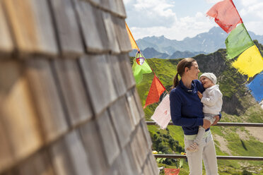 Deutschland, Bayern, Oberstdorf, glückliche Mutter mit kleiner Tochter auf einer von Wimpeln umgebenen Berghütte - DIGF05003