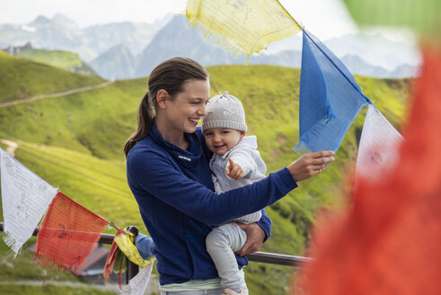 Deutschland, Bayern, Oberstdorf, glückliche Mutter mit kleiner Tochter auf einer von Wimpeln umgebenen Berghütte - DIGF05004