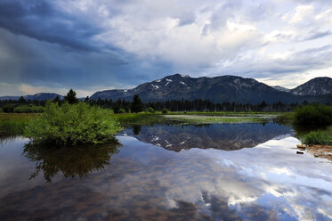 Mount Tallac and dramatic clouds reflect in a pool of water in the summer in Lake Tahoe, California. - AURF01425