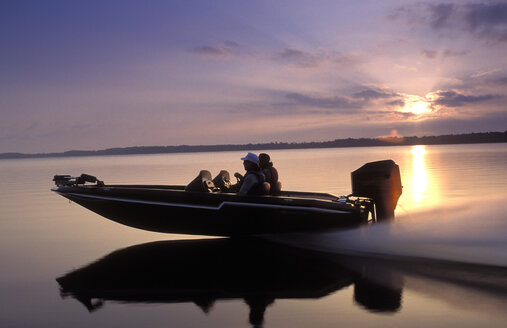 Men speed across open water in a boat. - AURF01437