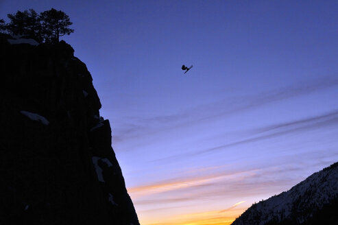 Der Profi-Skifahrer Josh Daiek vollführt bei Sonnenuntergang einen Frontflip beim BASE-Skispringen vom Lovers Leap in Strawberry, CA. - AURF01455