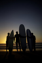 Silhouetten von Surfern am Strand, die den Sonnenuntergang beobachten. - AURF01496