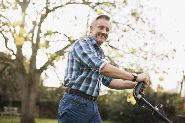 Portrait smiling senior man mowing lawn - HOXF03673