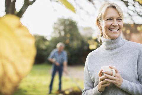 Porträt lächelnd, glücklich reife Frau trinken Kaffee im Herbst Hof, lizenzfreies Stockfoto