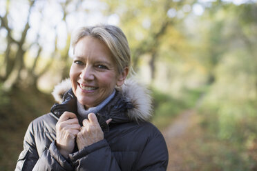 Porträt lächelnde, selbstbewusste reife Frau im Parka im Wald - HOXF03685