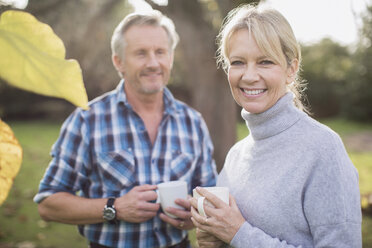 Portrait smiling, happy mature couple drinking coffee in backyard - HOXF03700