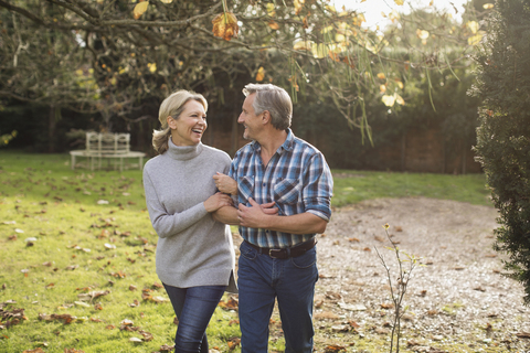 Glücklich, sorglos reifen Paar zu Fuß Arm in Arm in sonnigen Herbst Hinterhof, lizenzfreies Stockfoto