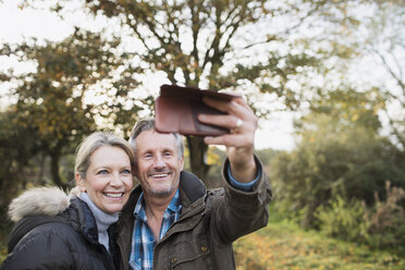 Glückliches reifes Paar nimmt Selfie mit Kamera-Handy im Herbst Wald - HOXF03730