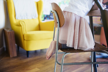 Cute barefoot girl in tutu kneeling on chair - HOXF03734