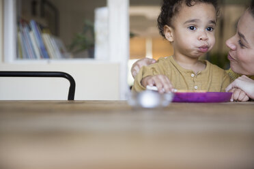 Mutter beobachtet süßen, unschuldigen Jungen beim Essen am Tisch - HOXF03737