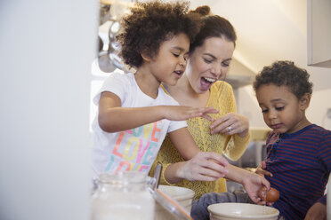 Verspielte Mutter und Kinder beim Backen in der Küche - HOXF03742