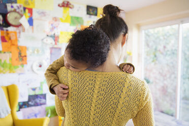 Liebevolle Mutter hält müden Babysohn - HOXF03758