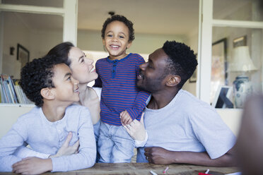 Porträt einer glücklichen Familie am Tisch - HOXF03761