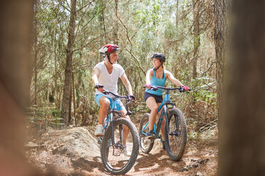 Vater und Tochter beim Mountainbiken auf einem Pfad im Wald - CAIF21332