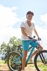 Portrait lächelnder, selbstbewusster reifer Mann beim Mountainbiking - CAIF21338