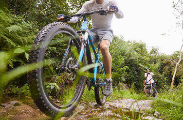 Mann beim Mountainbiken auf schlammigem Weg - CAIF21349