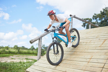 Konzentrierter reifer Mann beim Mountainbiking auf einer Hindernisbahn-Rampe - CAIF21350