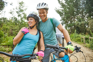 Glückliches, zärtliches junges Paar beim Mountainbiking - CAIF21359