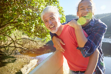 Portrait verspielter Vater und Sohn am sonnigen Sommersee - CAIF21367