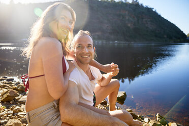 Porträt liebevolles, sorgloses Paar, das sich an einem sonnigen Sommersee die Hände hält - CAIF21370