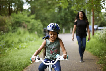 Mutter beobachtet Tochter beim Radfahren auf dem Weg - CAIF21383