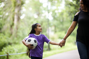 Zärtliche Mutter und Tochter mit Fußball, die sich an den Händen halten - CAIF21391