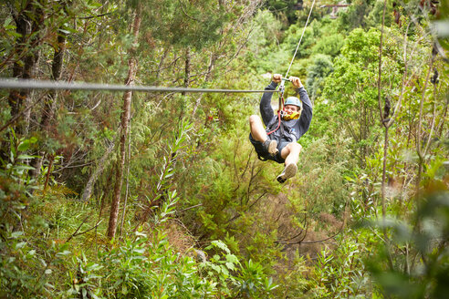 Mann Seilrutsche über Bäume im Wald - CAIF21409