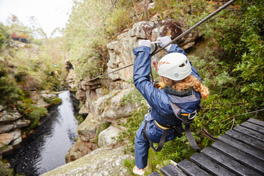 Frau zip lining über Teich im Wald - CAIF21417