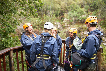 Friends talking, waiting to zip line in woods - CAIF21423