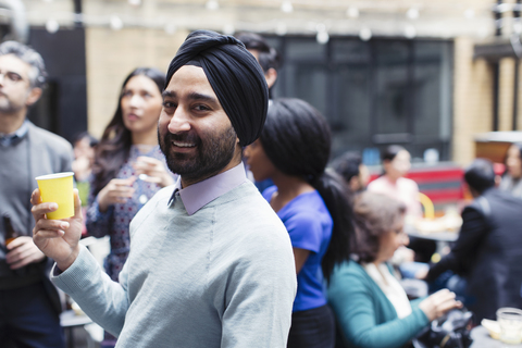 Porträt eines selbstbewussten Mannes mit Turban, der eine Party auf einer Terrasse genießt, lizenzfreies Stockfoto