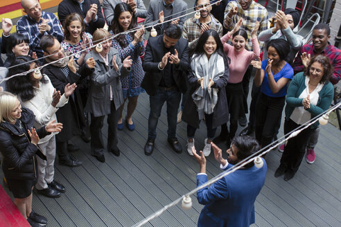 Business people clapping for businessman, celebrating on patio - CAIF21458