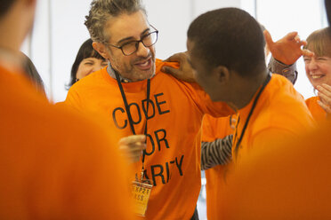 Glückliche Hacker, die sich umarmen und beim Hackathon für wohltätige Zwecke programmieren - CAIF21501