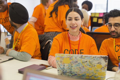 Hacker am Laptop programmieren beim Hackathon für wohltätige Zwecke, lizenzfreies Stockfoto