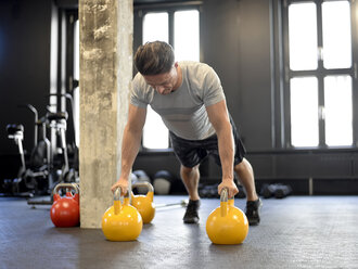 Man doing pushups on kettlebells at gym - BFRF01892