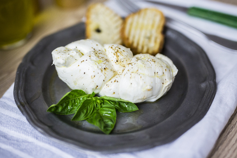 Mozzarella braid, basil and bread on plate stock photo