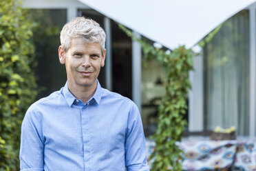 Portrait of content mature man with grey hair in front of his house - TCF05647