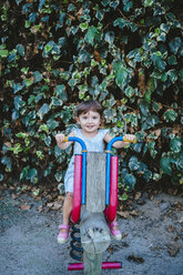 Baby girl enjoying at playground while riding a wooden motorbike - GEMF02334