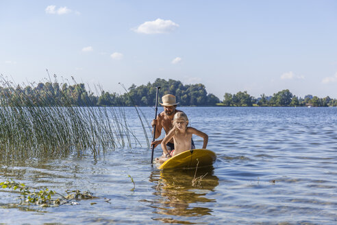 Father and daughter paddle boarding on lake - TCF05674