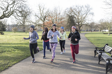 Smiling female runners running in sunny park - CAIF21600