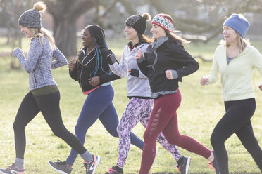 Smiling female runners running in sunny park - CAIF21602