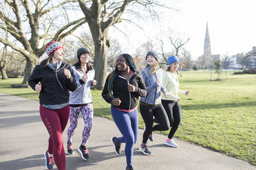 Lächelnde Läuferinnen laufen im sonnigen Park - CAIF21604