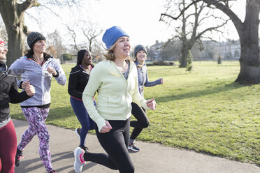 Lächelnde Läuferinnen laufen im sonnigen Park - CAIF21607