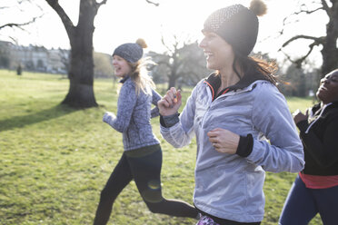 Smiling female runners running in sunny park - CAIF21608