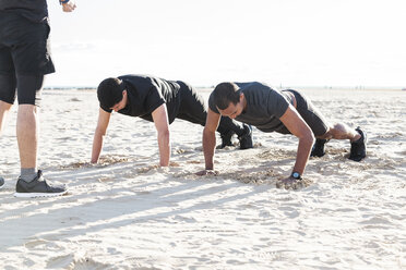 Männer machen Liegestütze am sonnigen Strand - CAIF21618