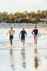 Begeisterte männliche Surfer laufen in der Brandung am Strand - CAIF21625