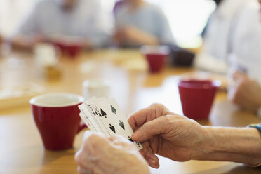 Close up ältere Frau spielt Karten mit Freunden im Gemeindezentrum - CAIF21653