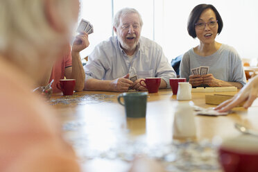 Senior friends playing games at table in community center - CAIF21654